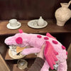 A person is holding a pink rainbow dragon plush toy, showcasing its soft texture and features.