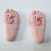 A pair of pink silicone feet shaped like pigs with tongues sticking out, used as a fidget toy.
