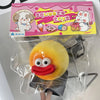 A yellow squishy toy shaped like a smiling face is packaged in a pink box labeled squeeze toys.