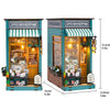 A wooden DIY book nook kit featuring a storefront display with miniature furniture and books.