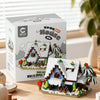 A box set of modern flash building blocks depicting a forest cabin with a greenhouse and windmill.