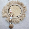 A personalized wooden baby pacifier clip featuring silicone beads and a natural fiber wreath with the word hello world.
