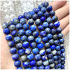A hand holds a strand of deep blue and gray natural stone beads for DIY jewelry making.
