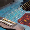 Close-up of a blue acoustic guitar with golden strings and a wooden string changer tool.