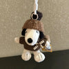 A brown knitted Snoopy plush keychain charm hanging from a white string.