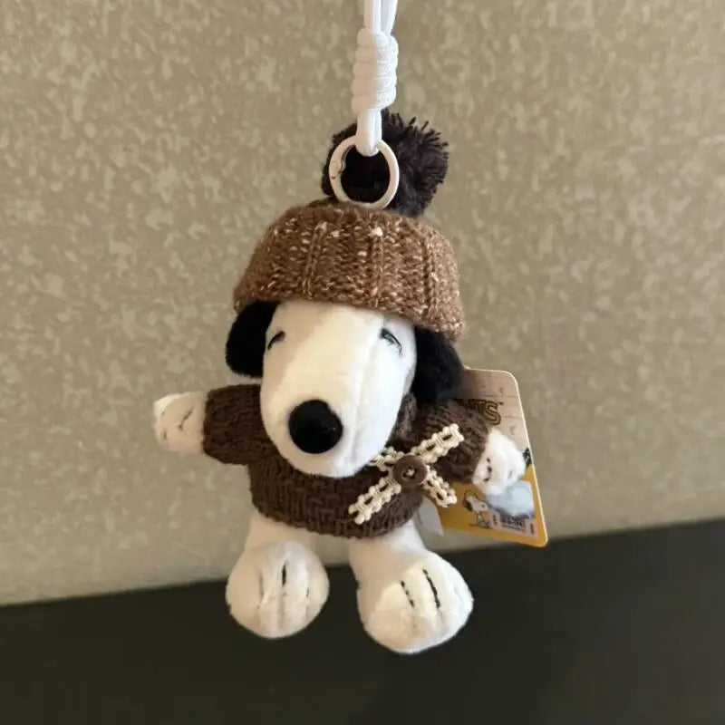 A brown knitted Snoopy plush keychain charm hanging from a white string.