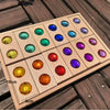 A wooden block set featuring various colored acrylic gemstones arranged in a grid on a wooden surface.