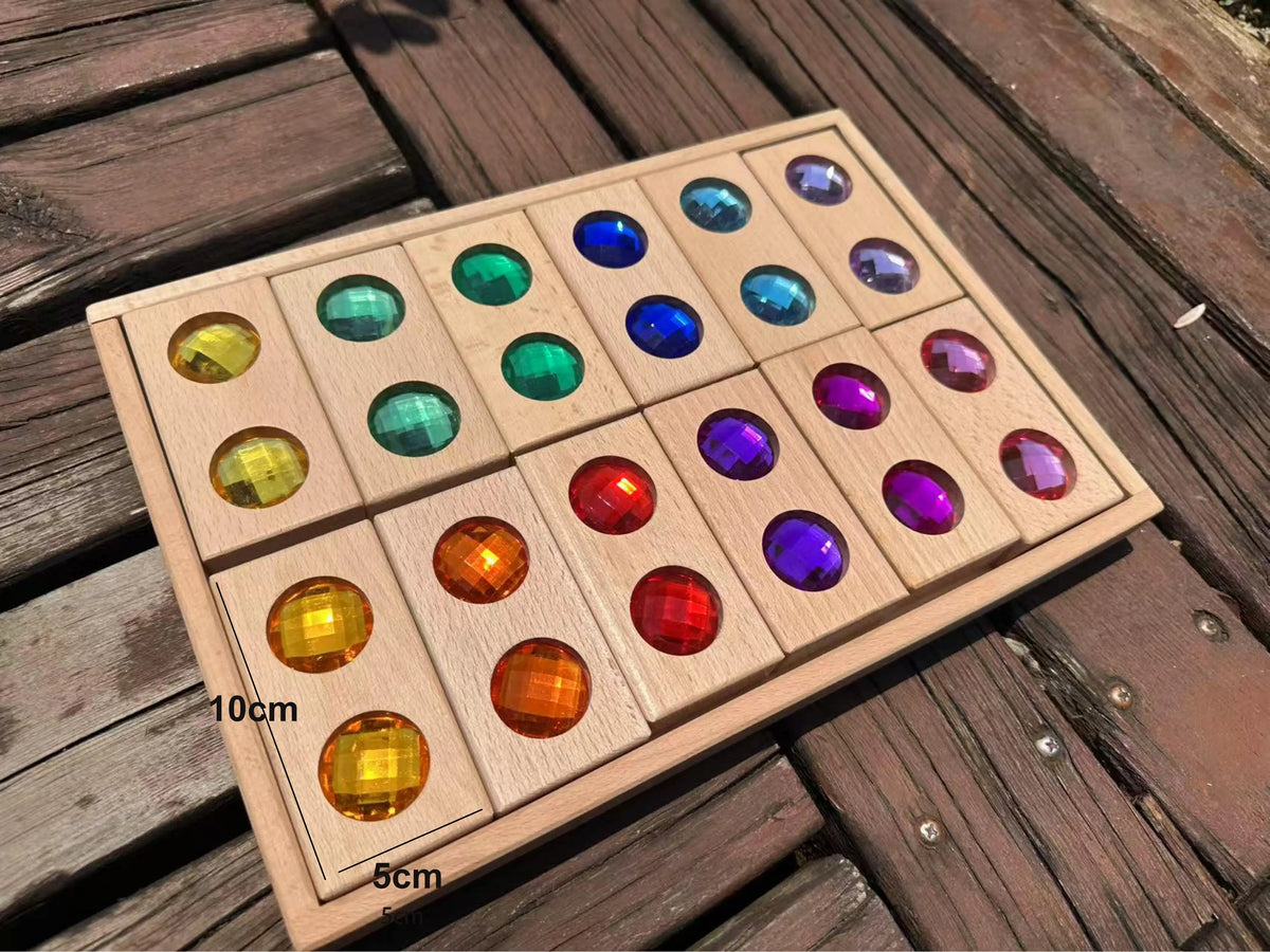 A wooden block set featuring various colored acrylic gemstones arranged in a grid on a wooden surface.