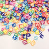 A colorful mix of polymer clay letter sprinkles in various shapes and colors scattered on a white surface.