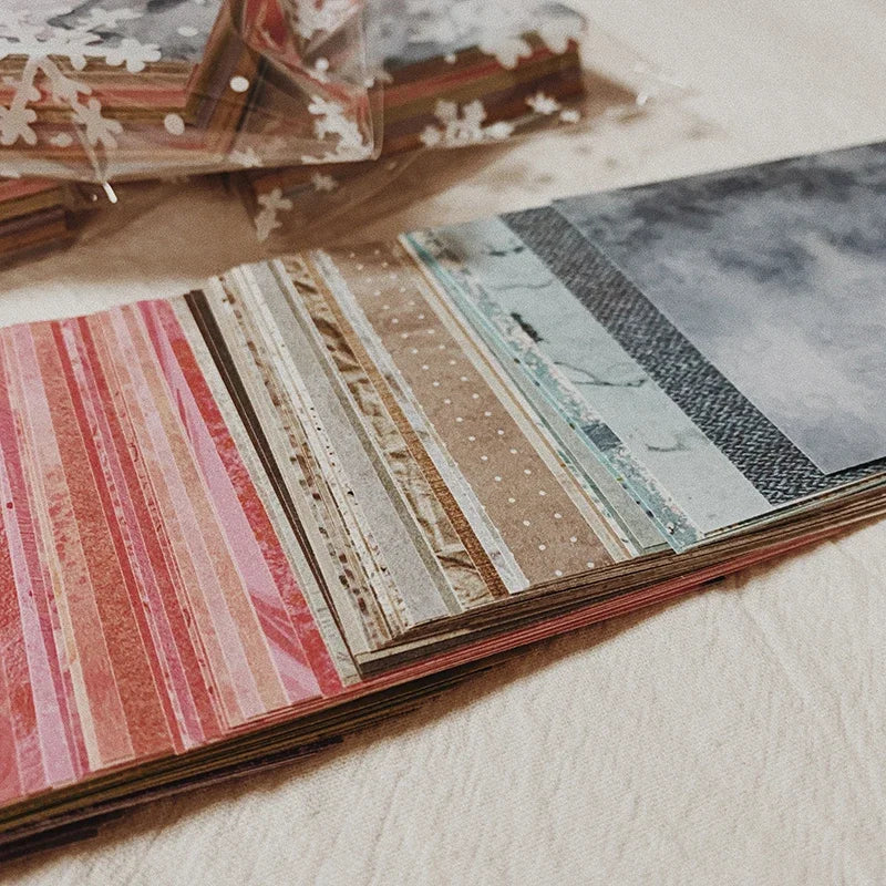 A close-up of a stack of rainbow textured paper sheets with various stripes and patterns for junk journals.