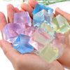 A hand holds several translucent, geometric ice cube squishy fidget toys in shades of blue, pink, and green.