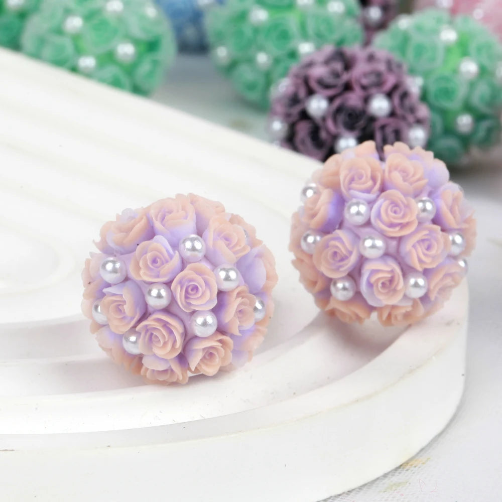 A cluster of light pink rose flower ball acrylic beads with pearl accents on a white surface.