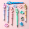 A collection of colorful 3D silicone bear focal beads and various sized pens are displayed on a pink background.