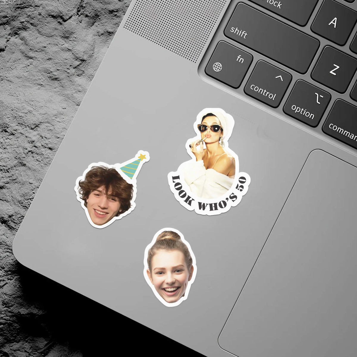 Die-cut vinyl stickers featuring a woman and a party hat placed on a silver laptop keyboard