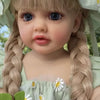 A realistic silicone vinyl toddler doll named Betty with light brown hair styled in braids and wearing a green sheer dress.