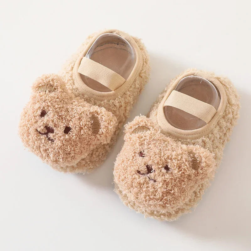 Pair of soft, beige cartoon bear baby booties with fabric straps for first steps