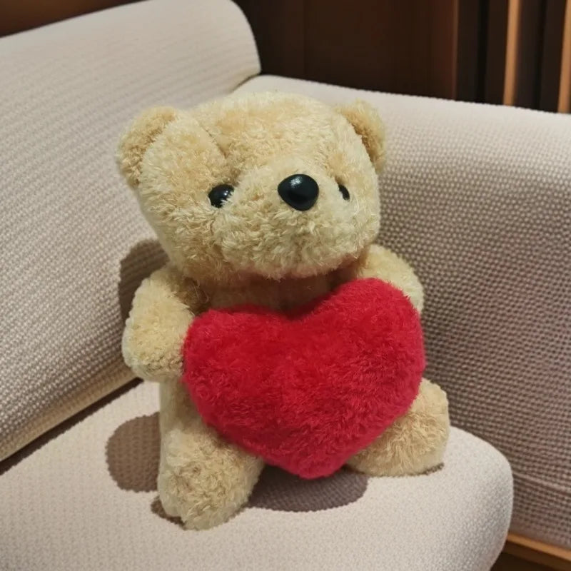 A fluffy beige plush bear holding a bright red heart on a light-colored surface.