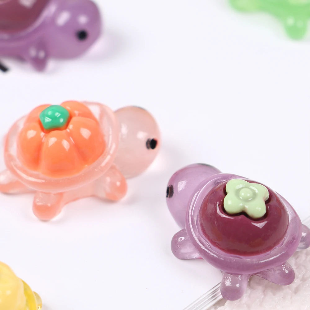 A set of mini glow-in-the-dark turtle resin figurines in various colors like purple, orange, and pink.