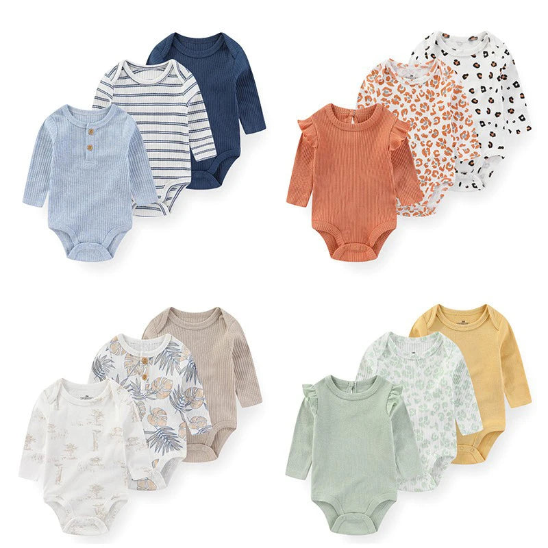 A collection of three cotton baby bodysuits with long sleeves in various patterns and solid colors.
