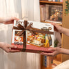 A box of a miniature dollhouse kit featuring a cozy baking kitchen set with wooden furniture and food items.