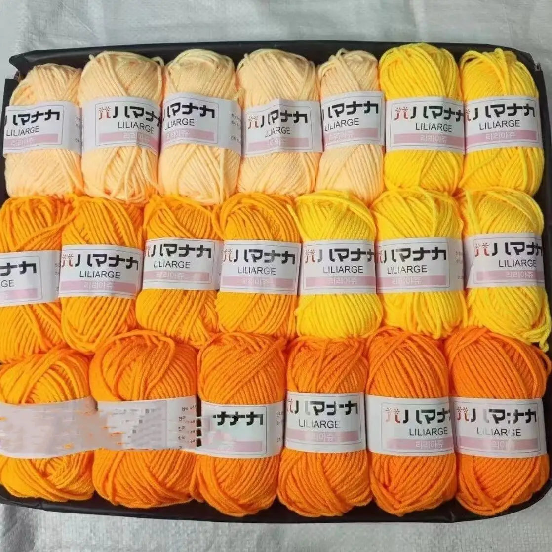A pack of 20 skeins of bright orange and yellow acrylic yarn for knitting and crochet projects.