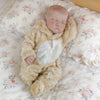 A realistic 18-inch vinyl reborn baby doll wearing a fluffy bear outfit sleeping on a floral patterned fabric.