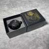 A black box containing a revolver-shaped metal dice set for RPG games with a gold emblem on the lid.