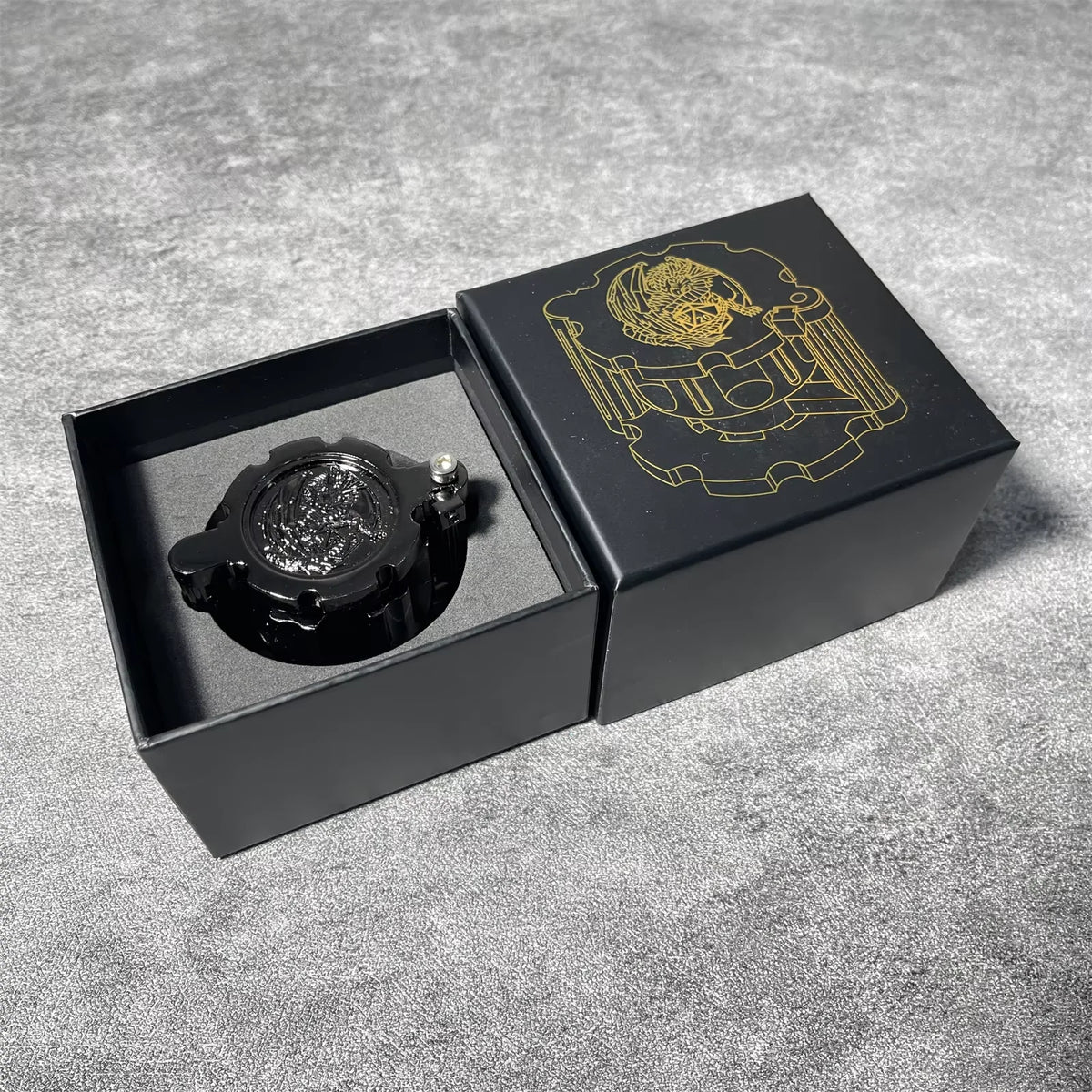 A black box containing a revolver-shaped metal dice set for RPG games with a gold emblem on the lid.