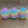 Trois œufs de dragon aux couleurs pastel pour la relaxation, disposés en rang sur une surface scintillante.