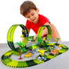 A young boy is interacting with a green and black dinosaur climbing car track set featuring various dinosaur vehicles.