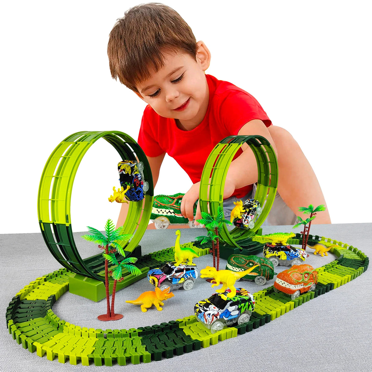 A young boy is interacting with a green and black dinosaur climbing car track set featuring various dinosaur vehicles.