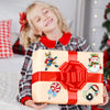 A smiling girl holds a gift box wrapped in red ribbon and gold paper, suggesting a diamond painting craft kit.
