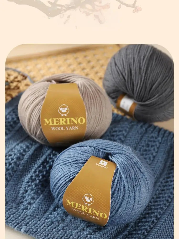 A close-up of a ball of grey merino wool yarn resting on a blue knitted fabric.