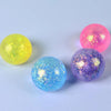 Three spherical glitter balls in yellow, pink, and blue are displayed on a white surface.