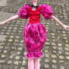 A doll fashion set featuring a red top and a pink patterned skirt with ruffled hem.