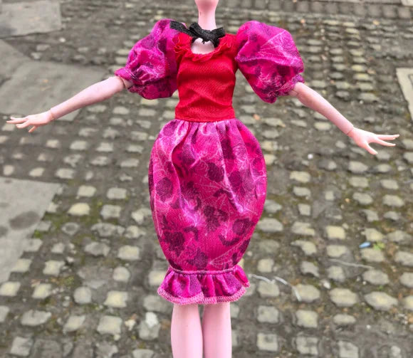 A doll fashion set featuring a red top and a pink patterned skirt with ruffled hem.