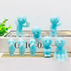 A collection of light blue glow-in-the-dark mini fitness figurines standing on a white surface.