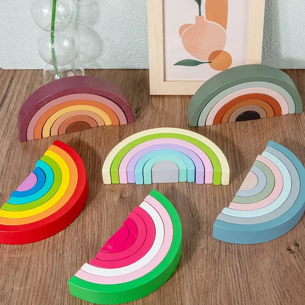 A collection of wooden rainbow arch bridge stacking blocks in various colors and shades arranged on a wooden surface.