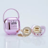 A pink silicone pacifier and clip set with a crown design and gold accents.