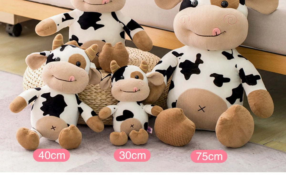A collection of soft plush cow stuffed animals in black and white patterns displayed on a light surface.