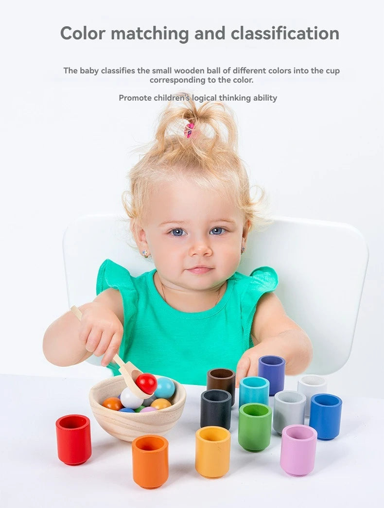 A baby is sorting wooden balls of different colors into corresponding cups for a color matching and classification activity.