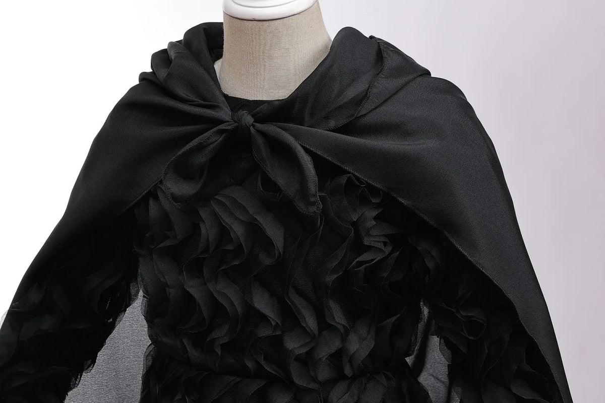 Black chiffon dress with ruffled sleeves and a dramatic black fabric drape worn by a mannequin.