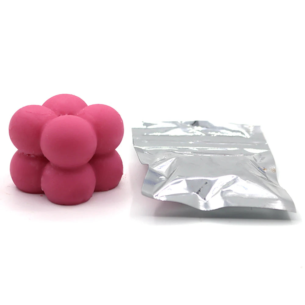 Pink candle dye chips in a cluster next to a piece of aluminum foil