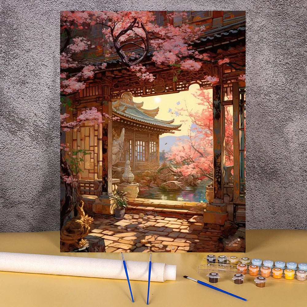 A paint by numbers kit depicting a traditional Japanese wooden house and flower field landscape with pink blossoms.