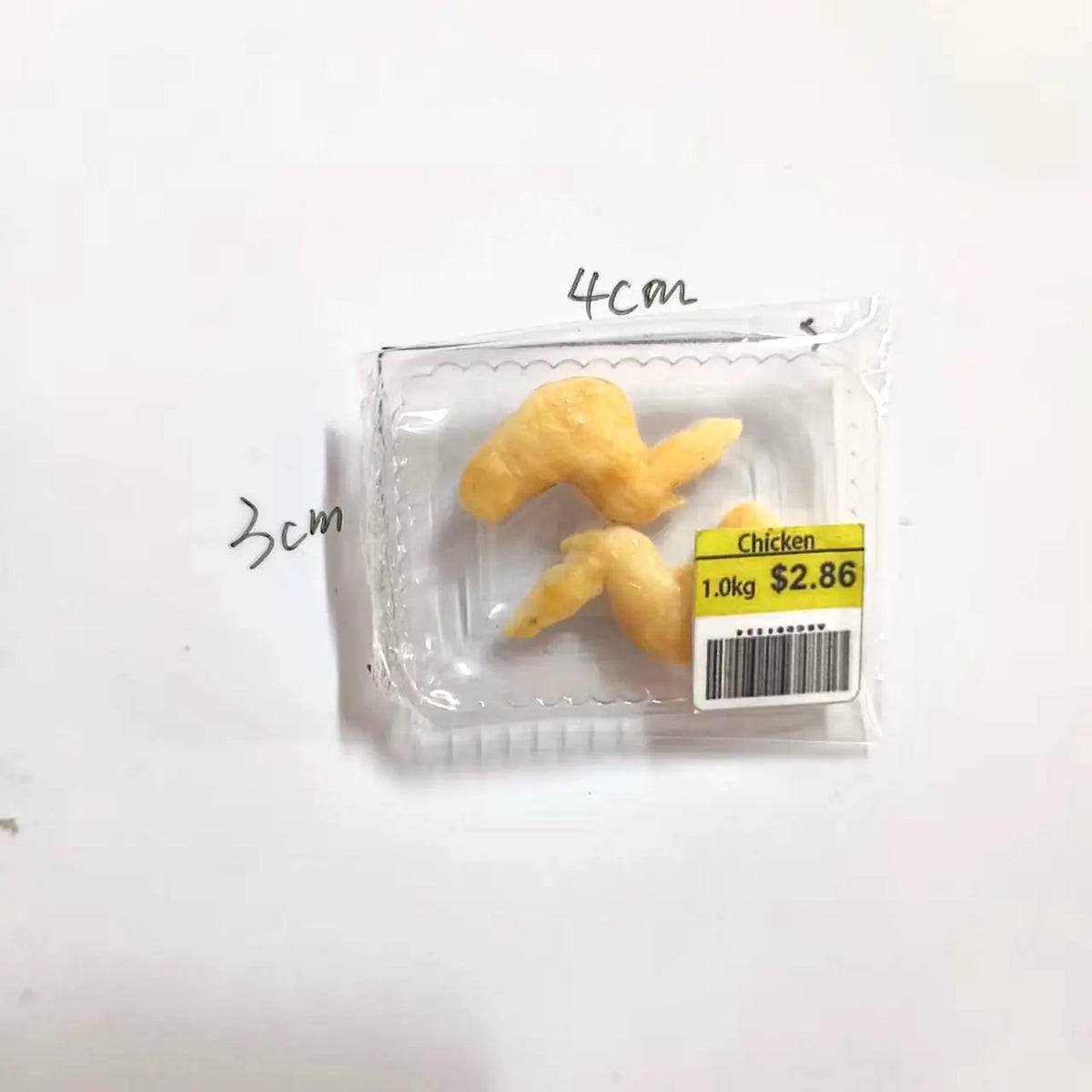 A clear plastic package containing a set of miniature food items including steak, salmon, and bacon rolls.