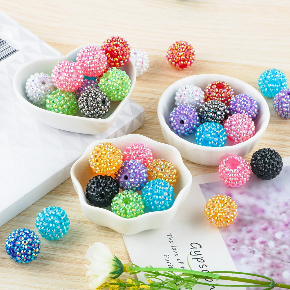 A collection of colorful rhinestone resin bayberry ball beads in various shades and sizes arranged on a wooden surface.