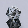 A translucent, faceted d20 polyhedral die with a pentagram symbol on one face, resting on a reflective surface.