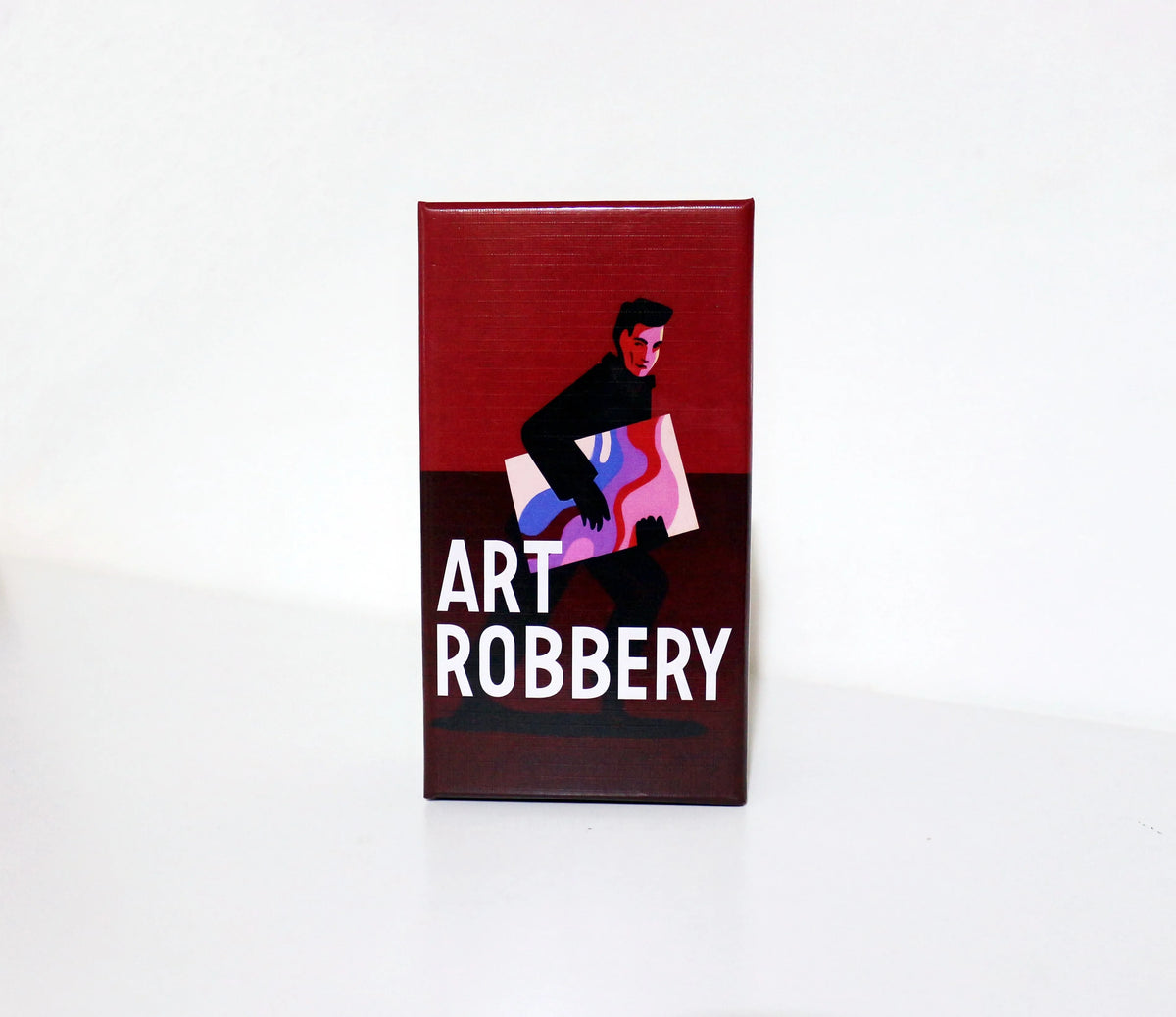 A rectangular box for the Art Robbery card game featuring a dark background and a silhouette of a person holding a painting.