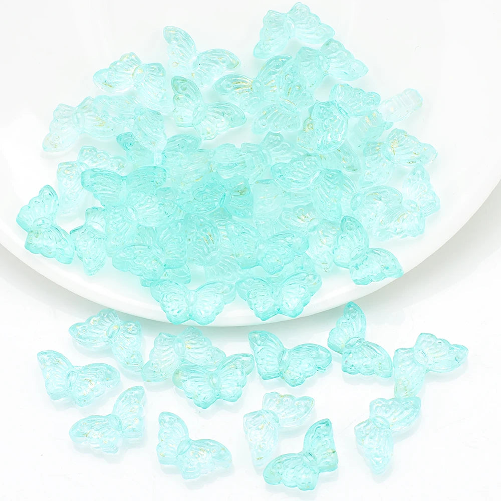 A pile of clear, light blue butterfly glass beads for jewelry making.