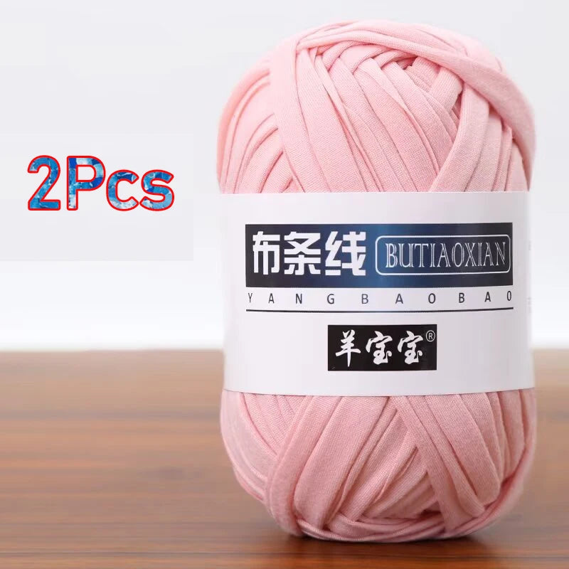 A skein of pink soft chunky t-shirt yarn is shown on a wooden surface.